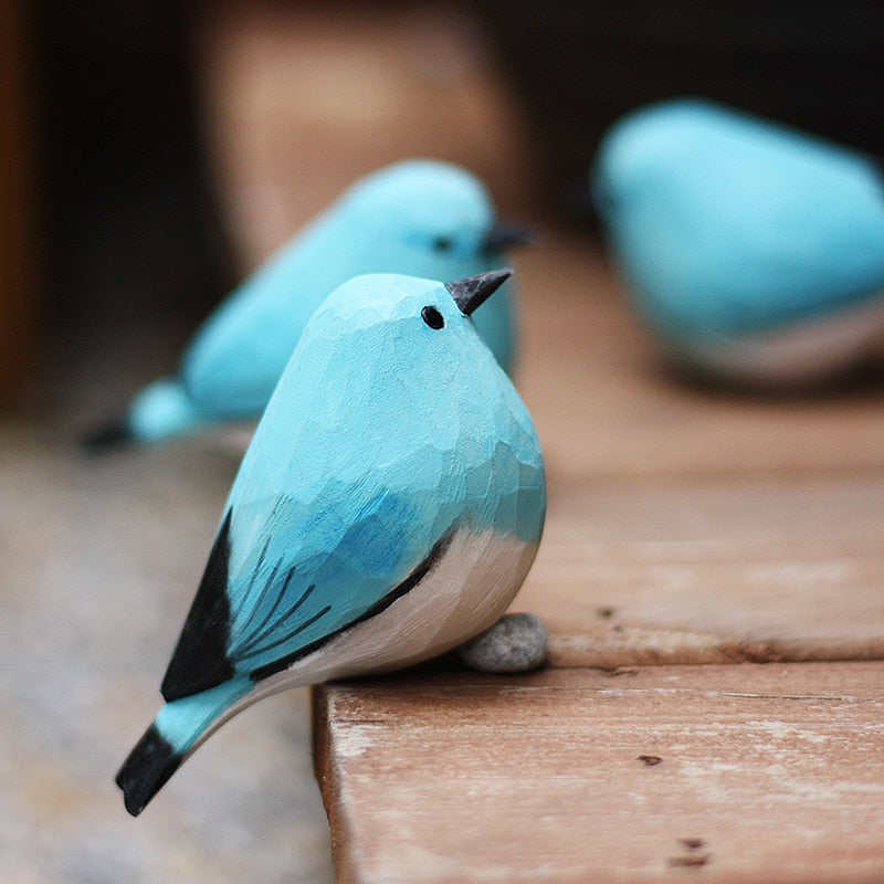 Handbeschilderd houten vogelbeeldje op een voetstuk