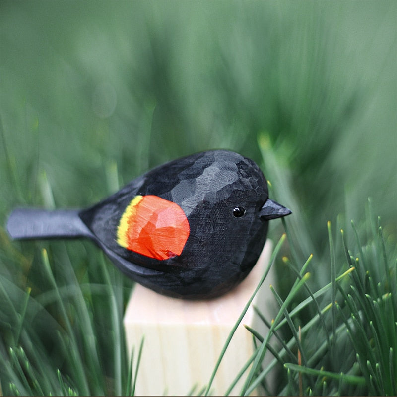 Handbeschilderd houten vogelbeeldje op een voetstuk